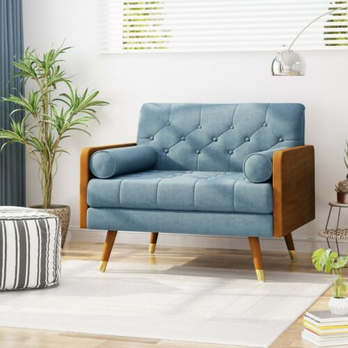Modern blue fabric club chair with wooden legs and armrests in a bright living room.