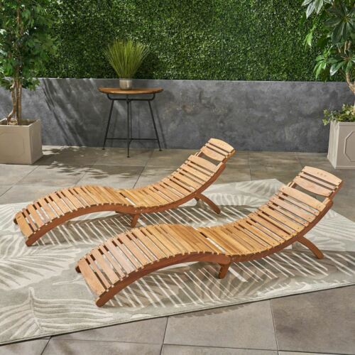 Two modern wooden lounge chairs on a patio with greenery backdrop.